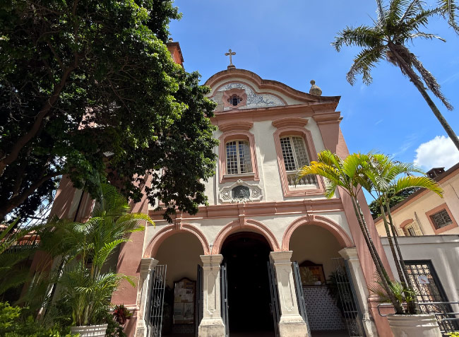 Imagem da fachada da igreja da PUC São Paulo com árvores ao lado esquerdo da imagem